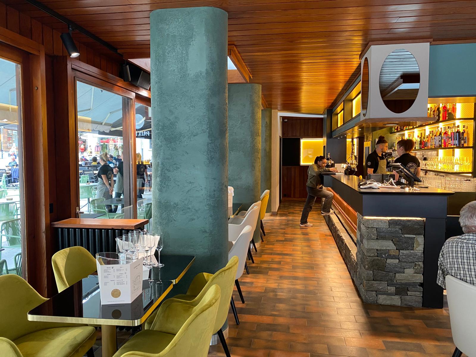 Le comptoir vu depuis la salle, tables et fauteuils verts