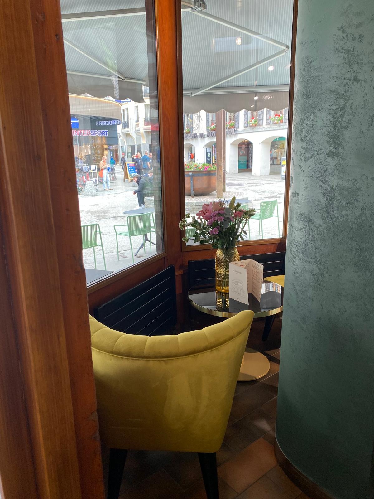 Un coin du comptoir près des fenêtres, fauteuil vert et table dressée
