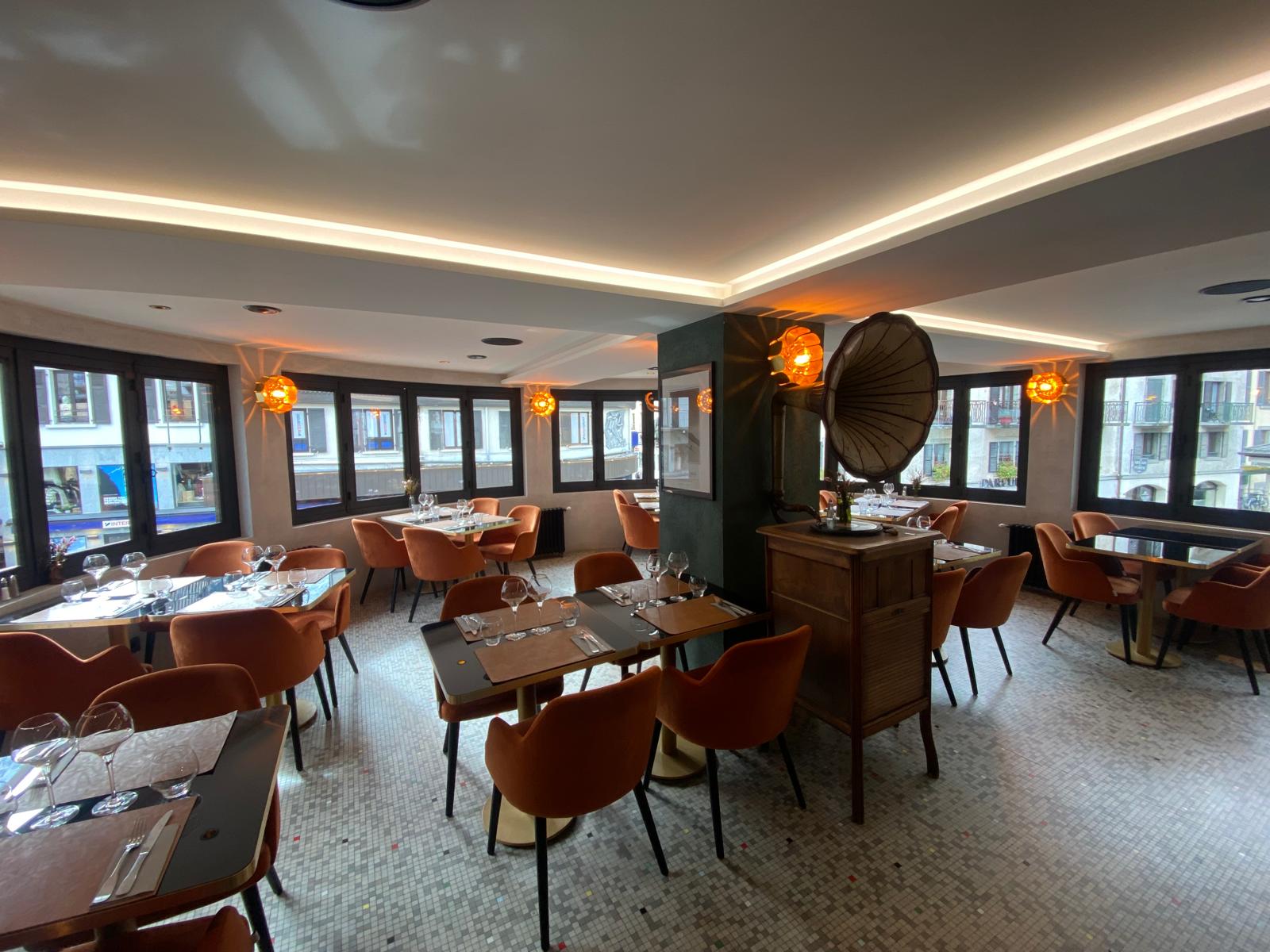 La salle panoramique avec ses tables dressées et ses fauteuils orangés